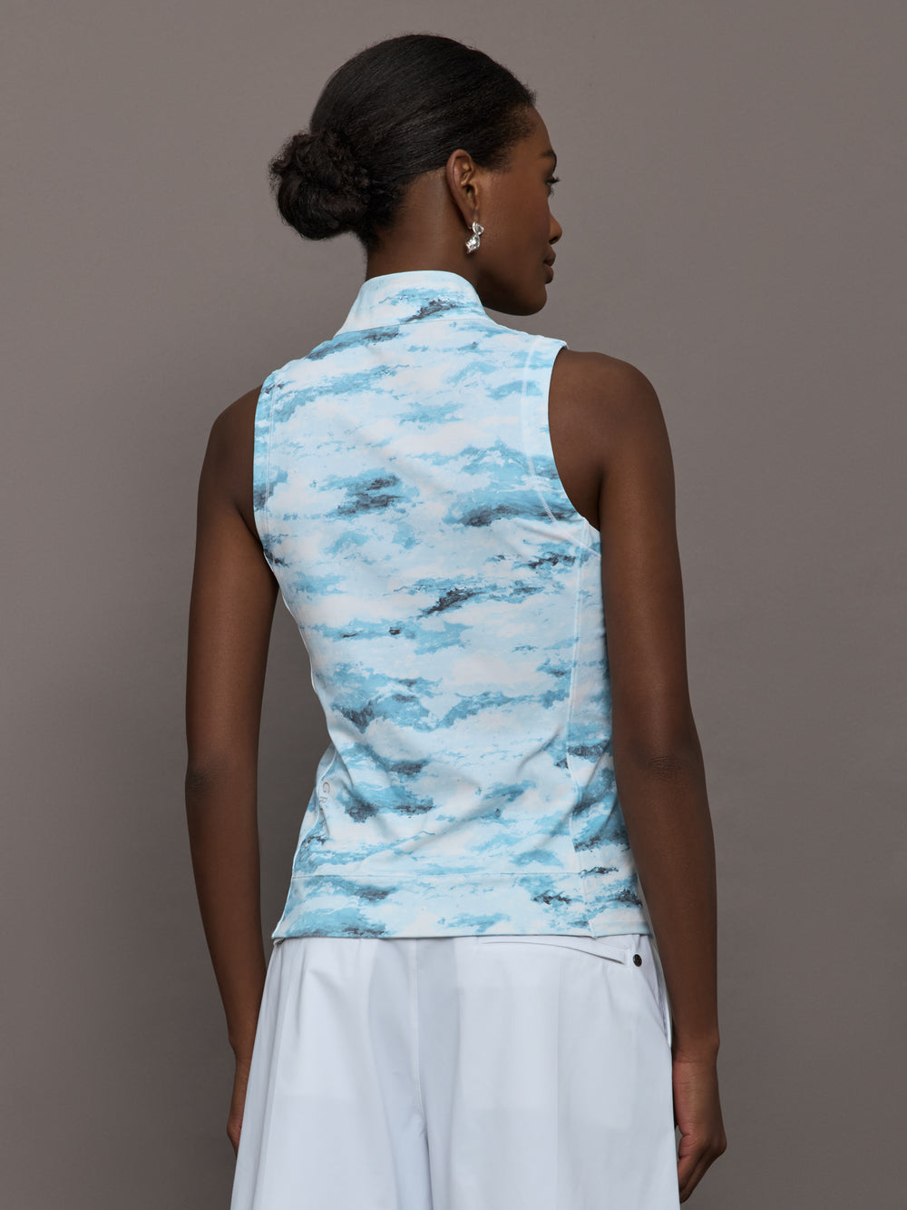 Model wears sleeveless quarter-zip top with a slim, athletic fit and a high collar.