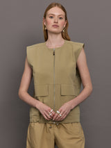 Model wears a wide shoulder, khaki zip up vest with tactical symmetrical front cargo pockets at the waist.