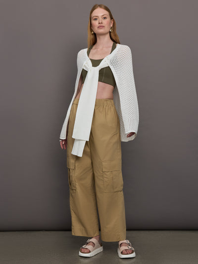 Model wears a sheer mesh white over the shoulder cape tied together at the front by sleeves. 