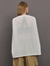 Model wears a sheer mesh white over the shoulder cape tied together at the front by sleeves. 