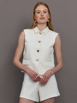Model wears a white collared tank with chunky gold buttons and symmetrical pockets below the waist.