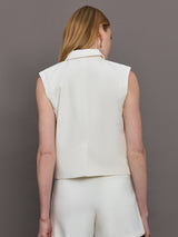 Model wears a white collared tank with chunky gold buttons and symmetrical pockets below the waist.