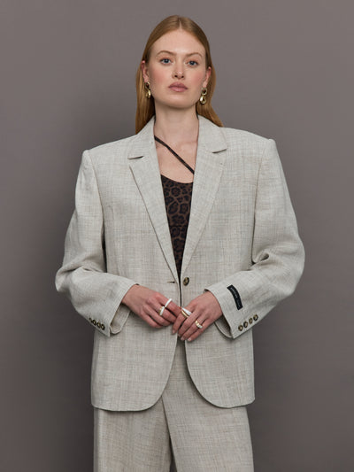 Model wears a gray/taupe textured oversized blazer with single button closure.