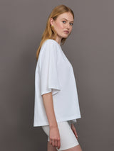 Model wears an oversized wide sleeve white tee shirt with red Herskind lettering across the chest.