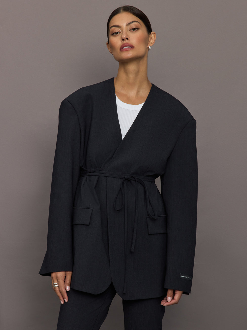 Model wearing a black blazer with a front tie.