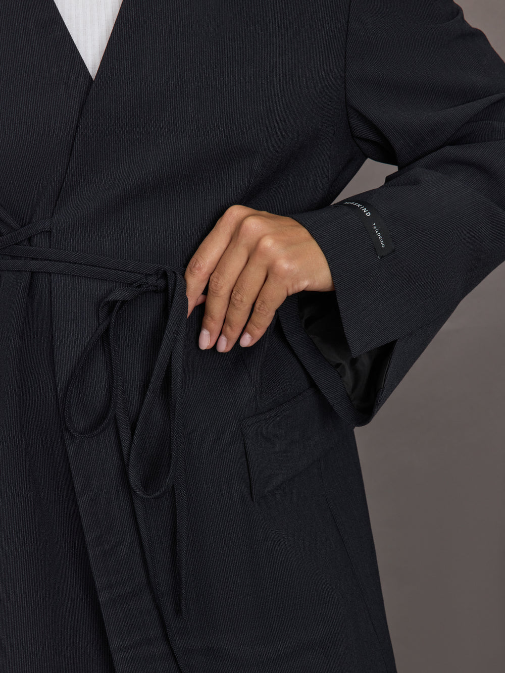 Model wearing a black blazer with a front tie.