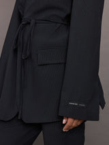 Model wearing a black blazer with a front tie.