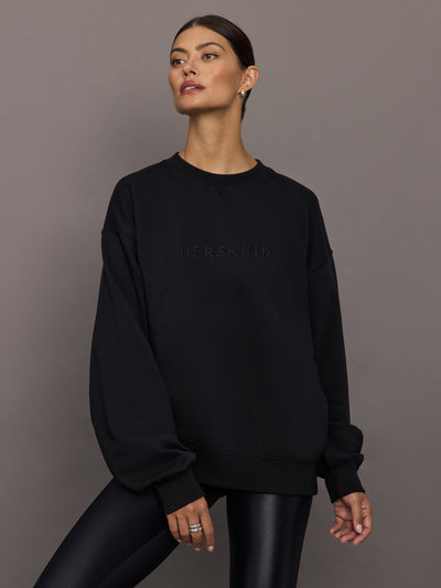 Model wearing a black blouse with 'Hershkind' branding.