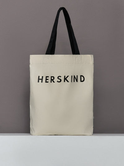 Beige tote bag with 'HERSKIND' text on a gray background