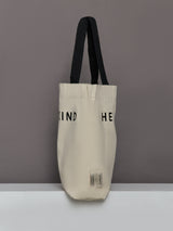 Beige tote bag with black text and handles on a gray background