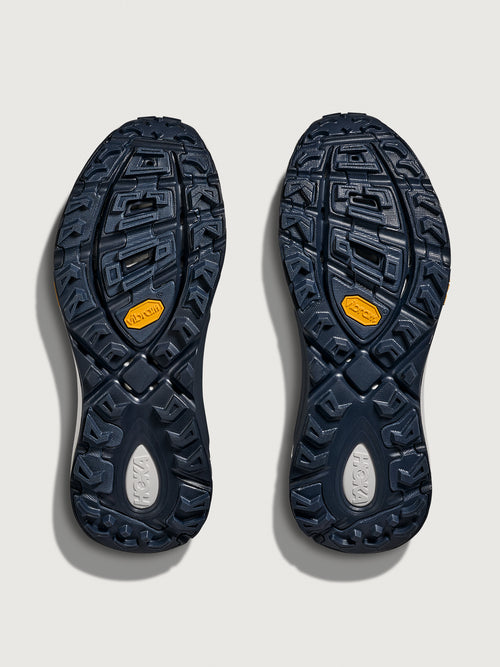 Close-up of a pair of black shoes with textured soles on a light gray background