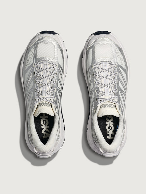 White running shoes with black soles on a light gray background