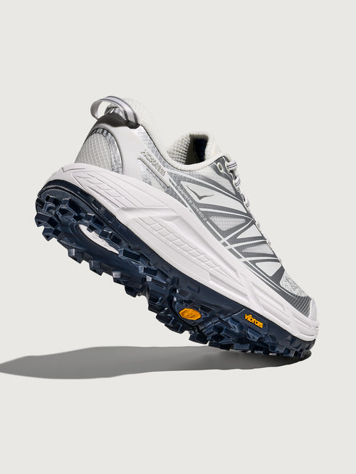 Gray and white athletic shoe with blue sole on a light gray background