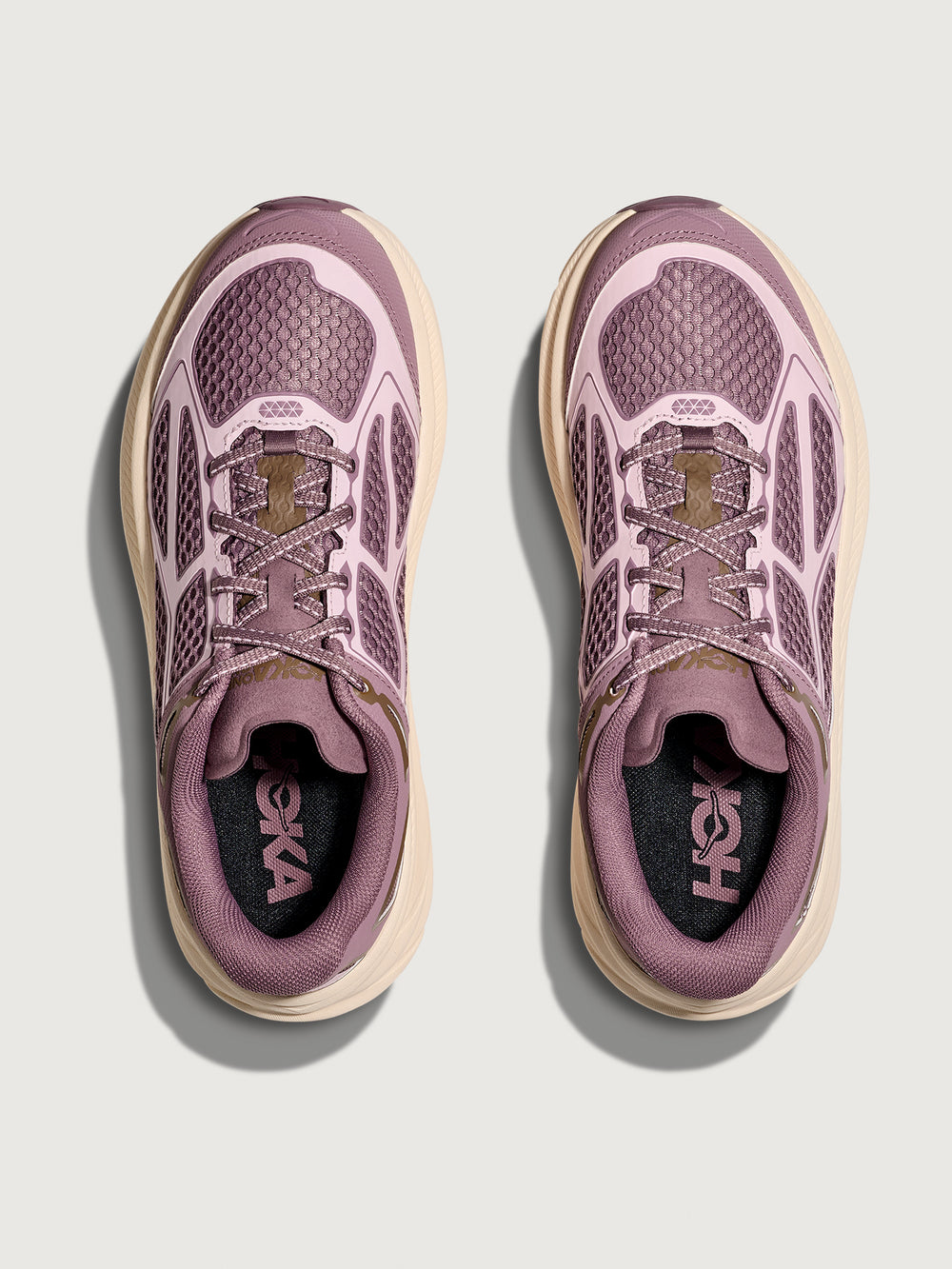Pair of pink running shoes with beige soles on a light gray background
