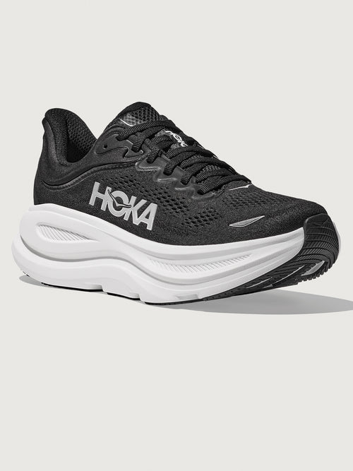 Black running shoe with white sole on a light gray background