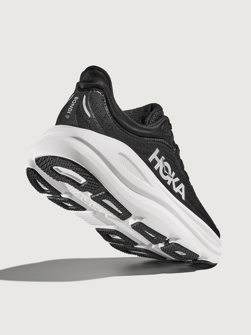 Black running shoe with white sole on a light gray background