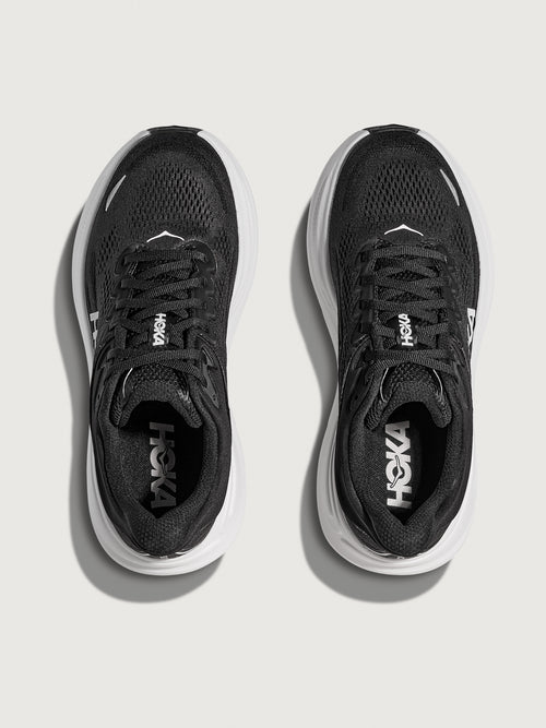 Black running shoe with white sole on a light gray background