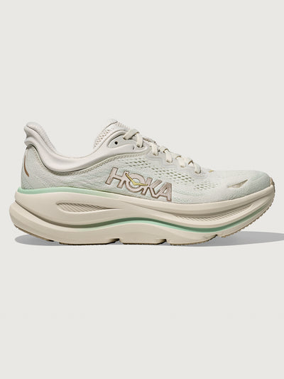 Chunky soled white Hoka running shoe with pastel green trim. 
