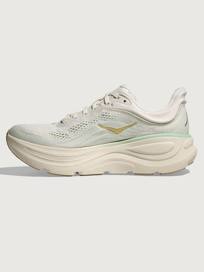 Chunky soled white Hoka running shoe with pastel green trim. 