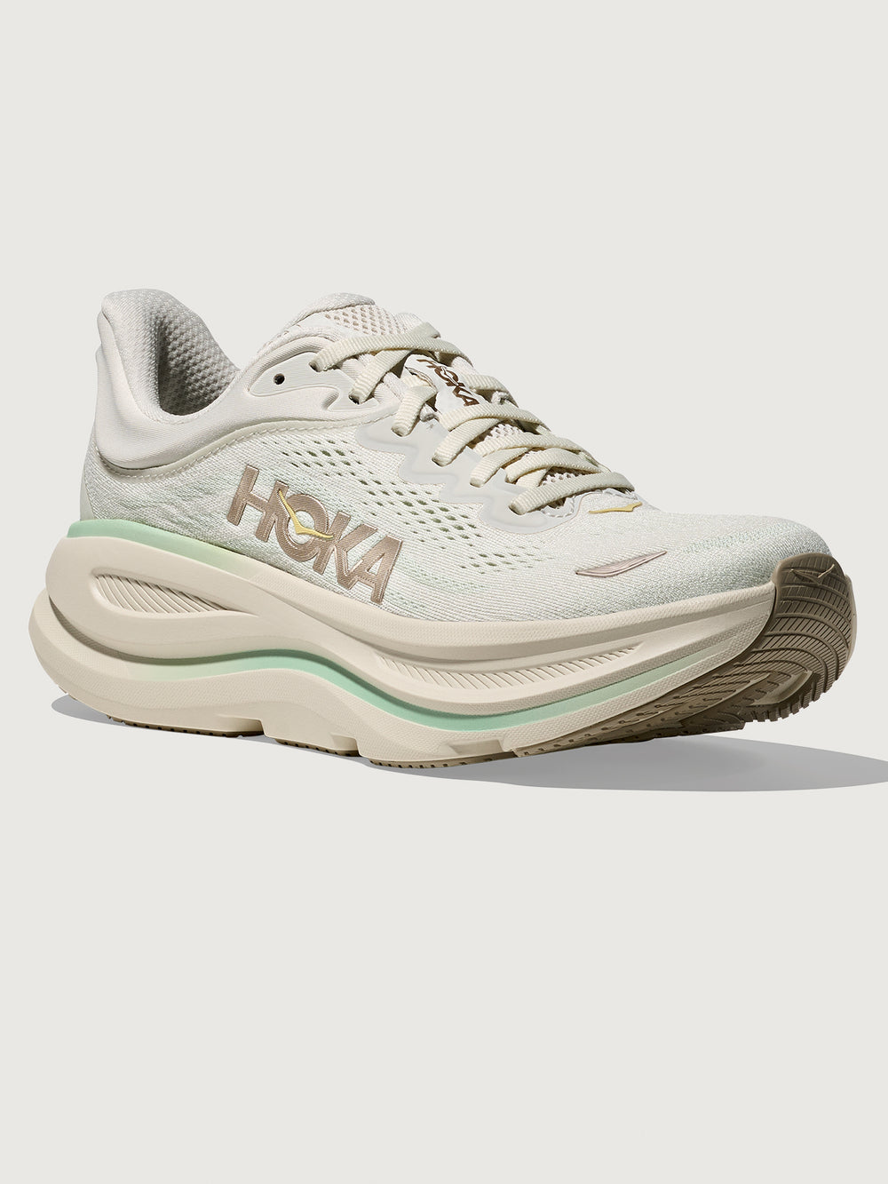 Chunky soled white Hoka running shoe with pastel green trim. 