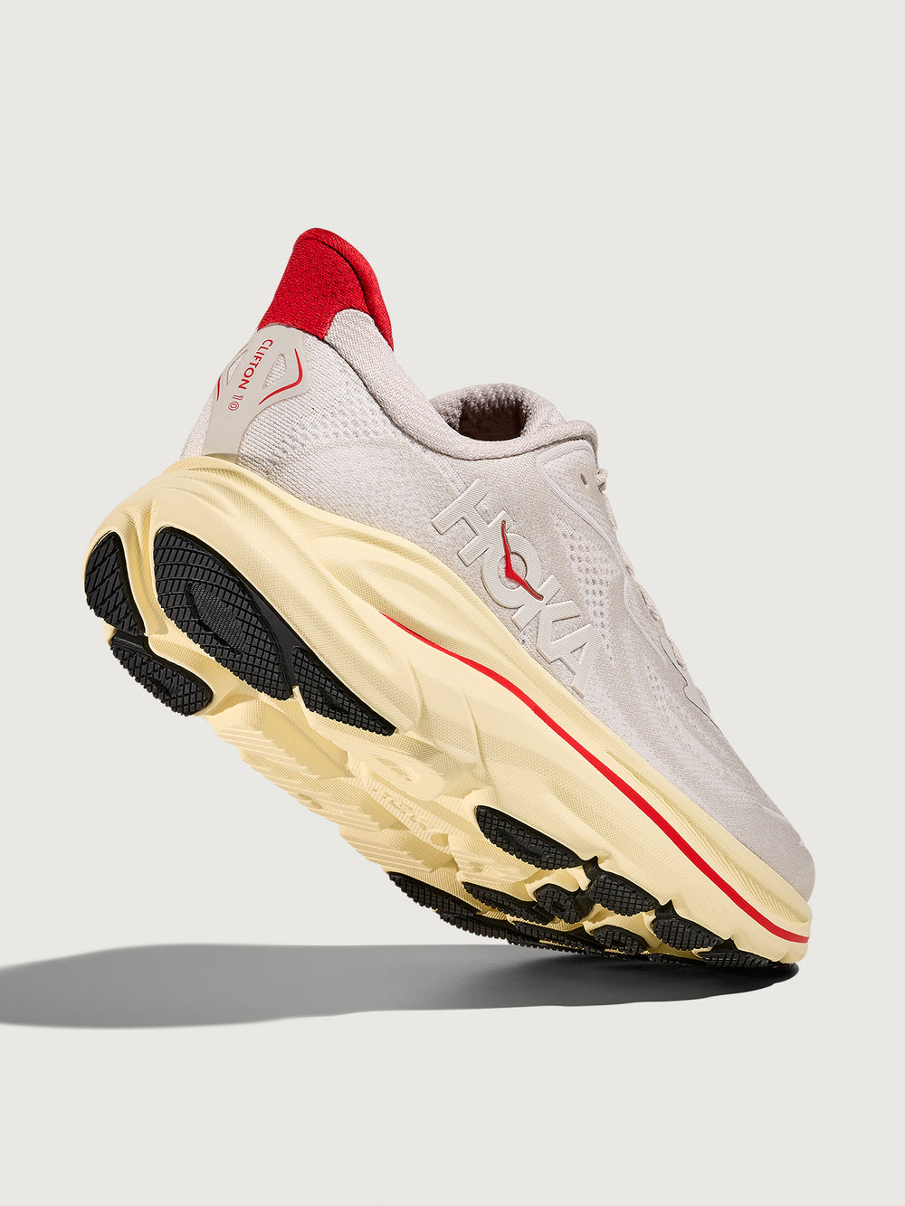 Gray running shoe with red accents with 'Hoka' logo on the side.