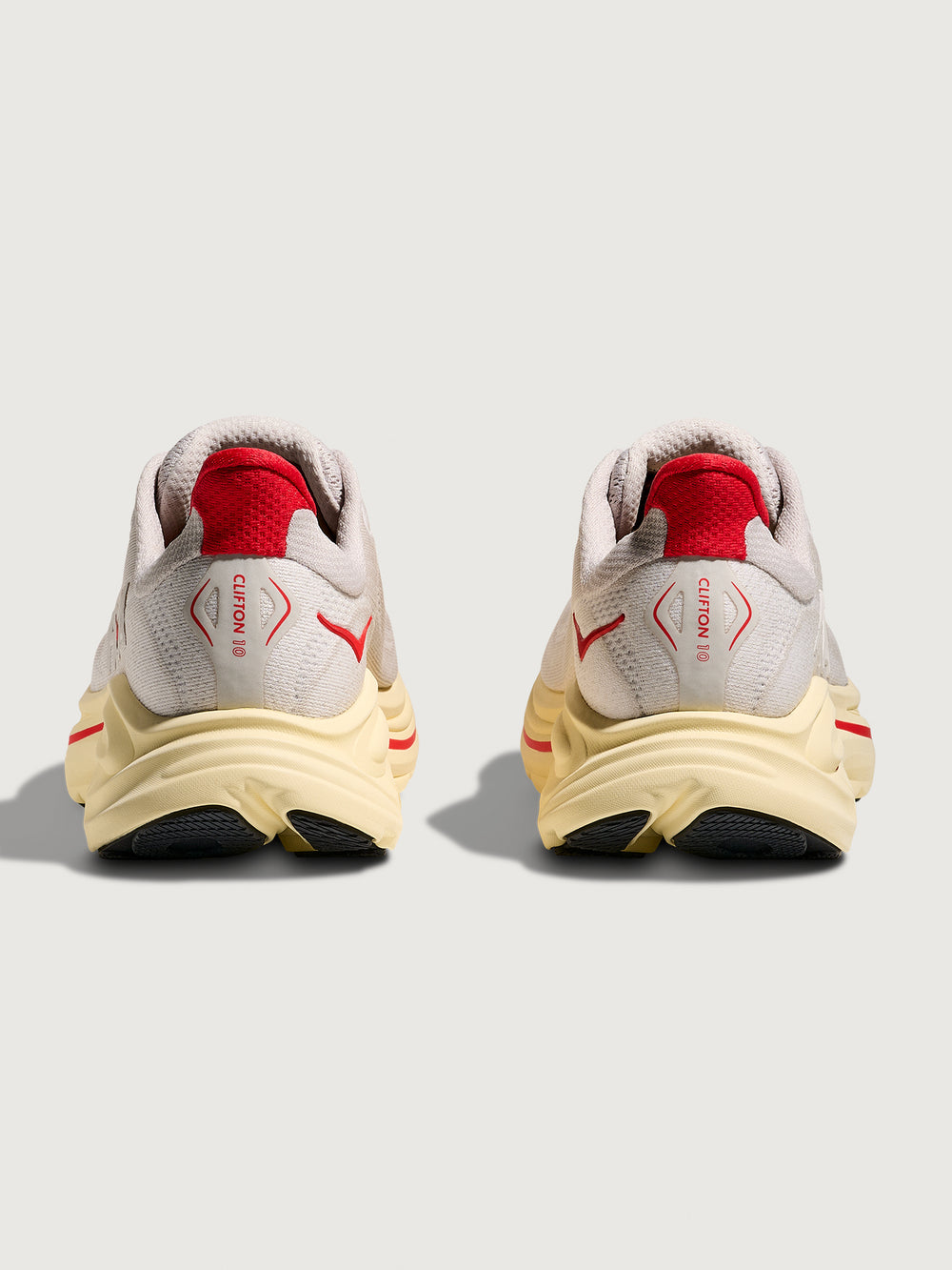 Gray running shoe with red accents with 'Hoka' logo on the side.