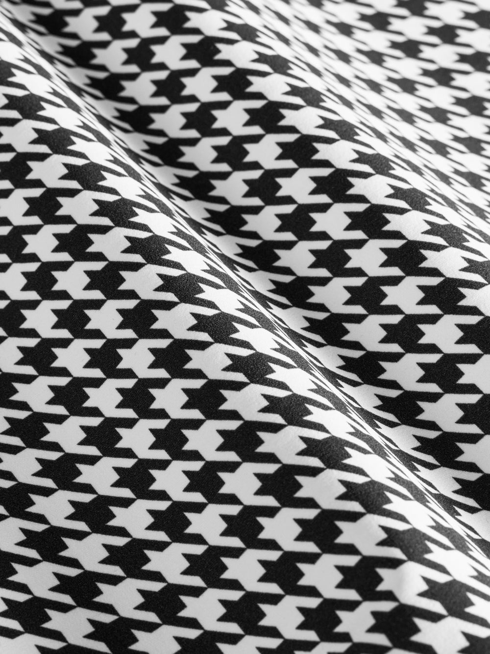 Close-up fabric detail of houndstooth print in black and white.