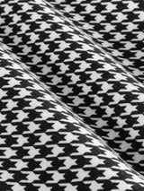 Close-up of houndstooth fabric in black and white with textured weave detail.
