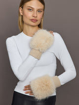 Model wearing beige faux fox knit mittens with ribbed cuffs, styled with white top.