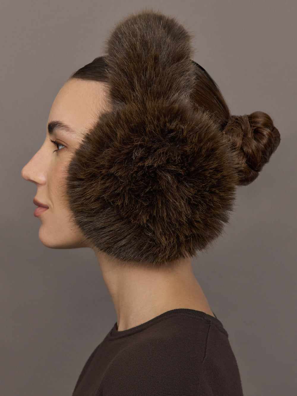 Model is wearing the Faux Fur Earmuffs Chocolate, side profile view.