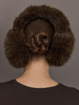 Model is wearing the Faux Fur Earmuffs Chocolate, back view.