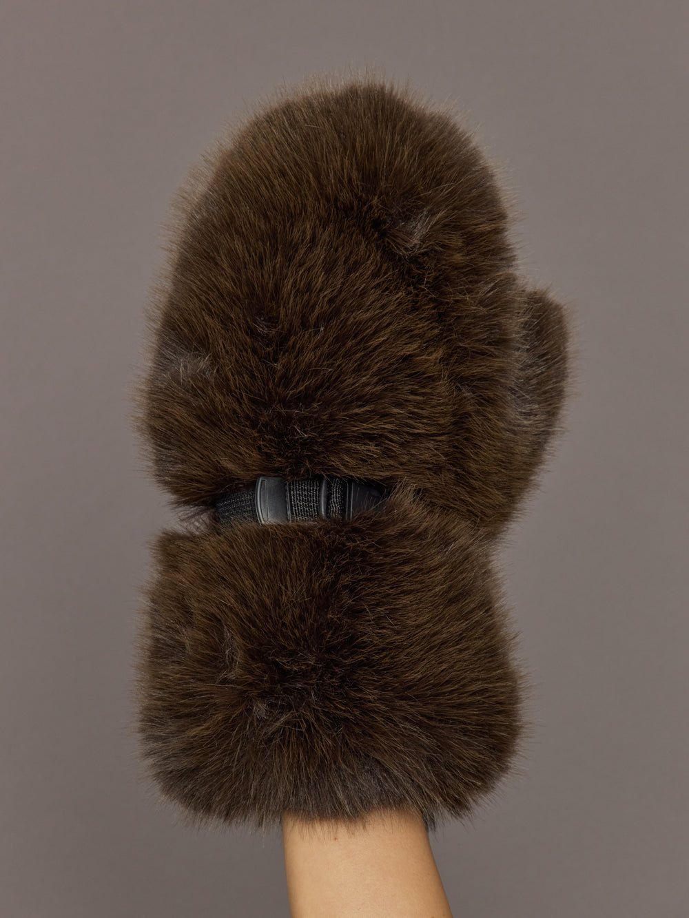 Model is holding the Faux Fur Fox Mitten Chocolate, front view of the faux fur exterior.
