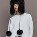 Model wearing Fox Trapper Hat in black faux fur, front view with pom-pom ties.