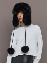 Model wearing Fox Trapper Hat in black faux fur, front view with pom-pom ties.