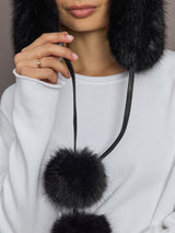Close-up of Fox Trapper Hat in black with pom-pom tie detail.