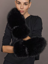 Model wearing black faux fur mittens, arms crossed, front view.