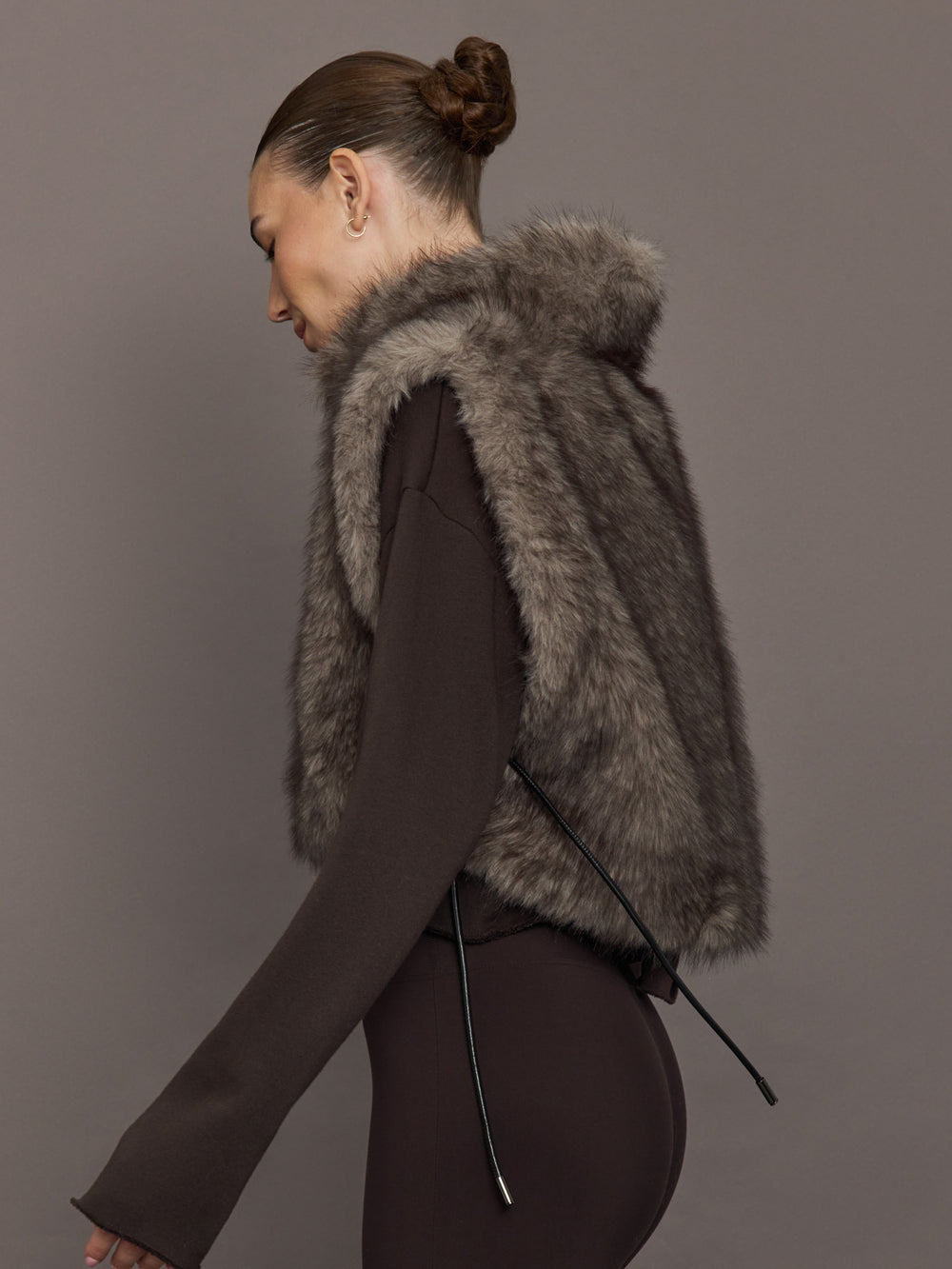 Model is wearing the Faux Fur Pullover Vest with Side Ties Mocha, side profile.

