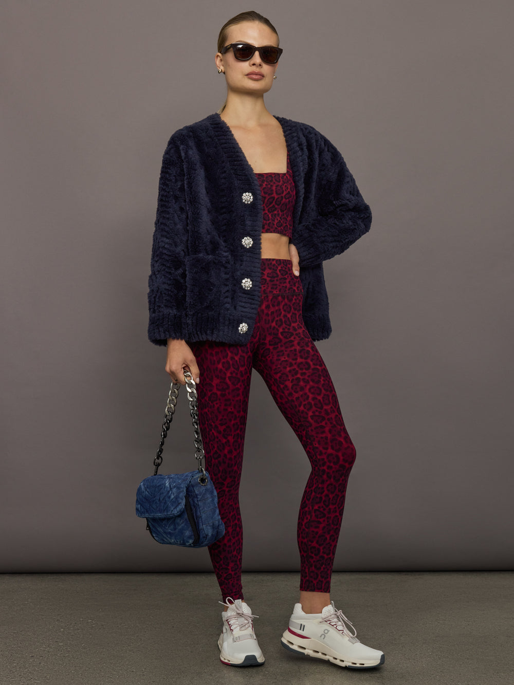 Full outfit view of navy faux fur cardigan styled with red leopard leggings and sneakers.