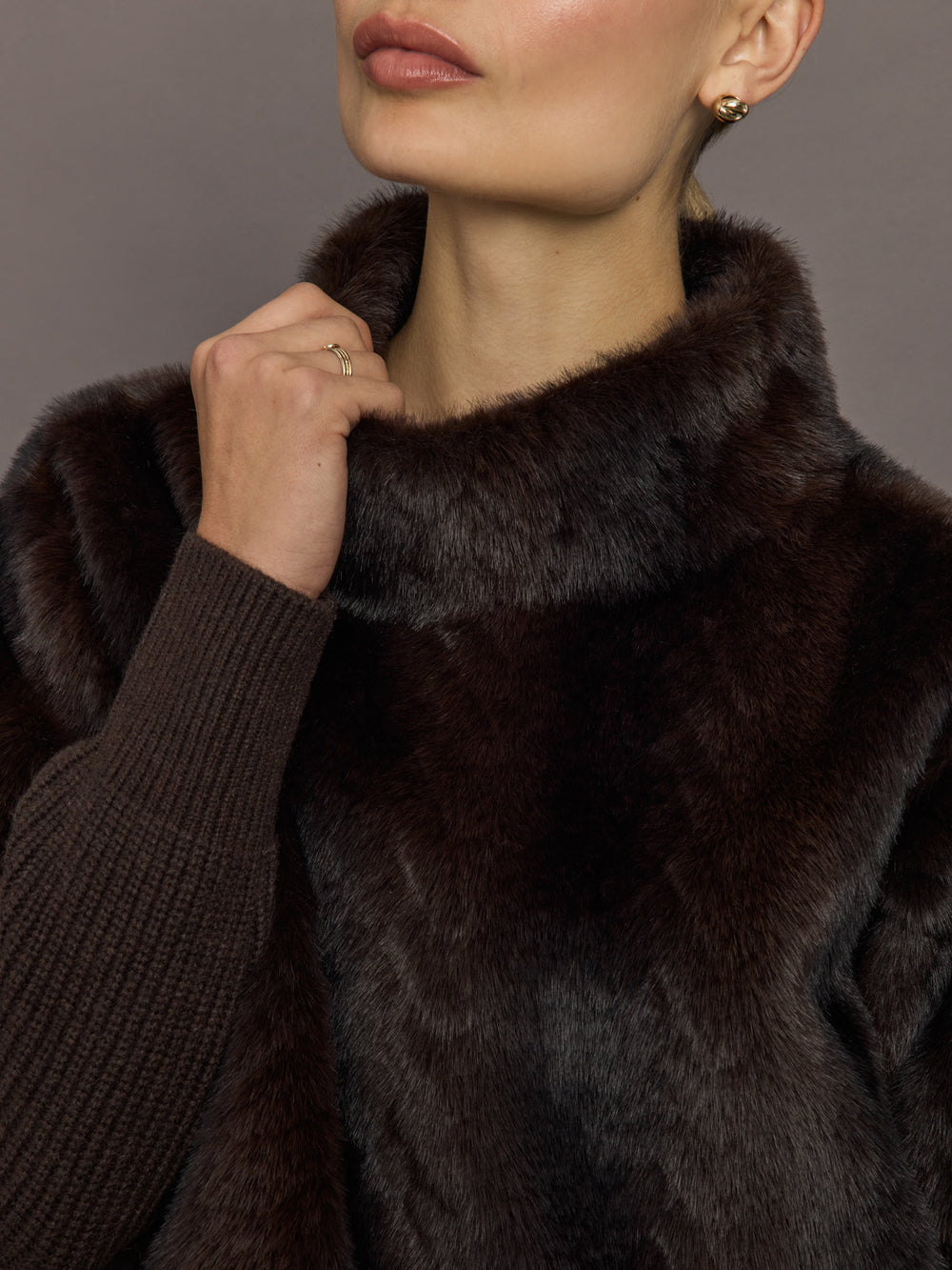 Close-up of dark brown faux fur pullover sweatshirt showing high collar detail.