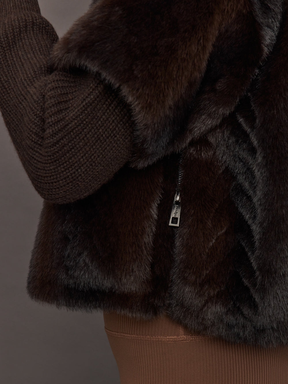 Close-up of side zipper detail on dark brown faux fur pullover sweatshirt.