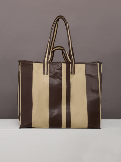 Beige canvas tote bag with black leather bindings, two straps, and an inner pocket.




