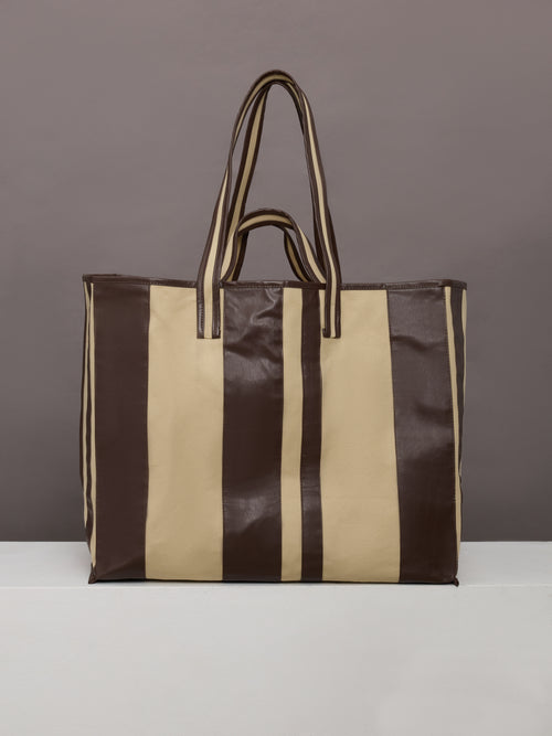Beige canvas tote bag with black leather bindings, two straps, and an inner pocket.




