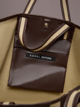 Beige canvas tote bag with black leather bindings, two straps, and an inner pocket.
