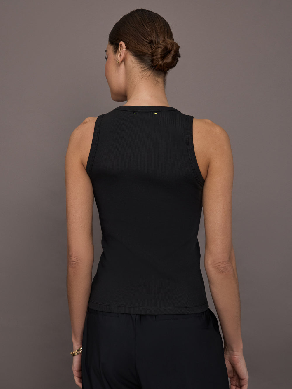 Model is wearing KR Ribbed Performance Tank in black, back view.