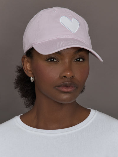 Model wearing a light purple cap with a white heart logo