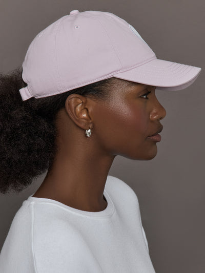 Model wearing a light purple cap with a white heart logo