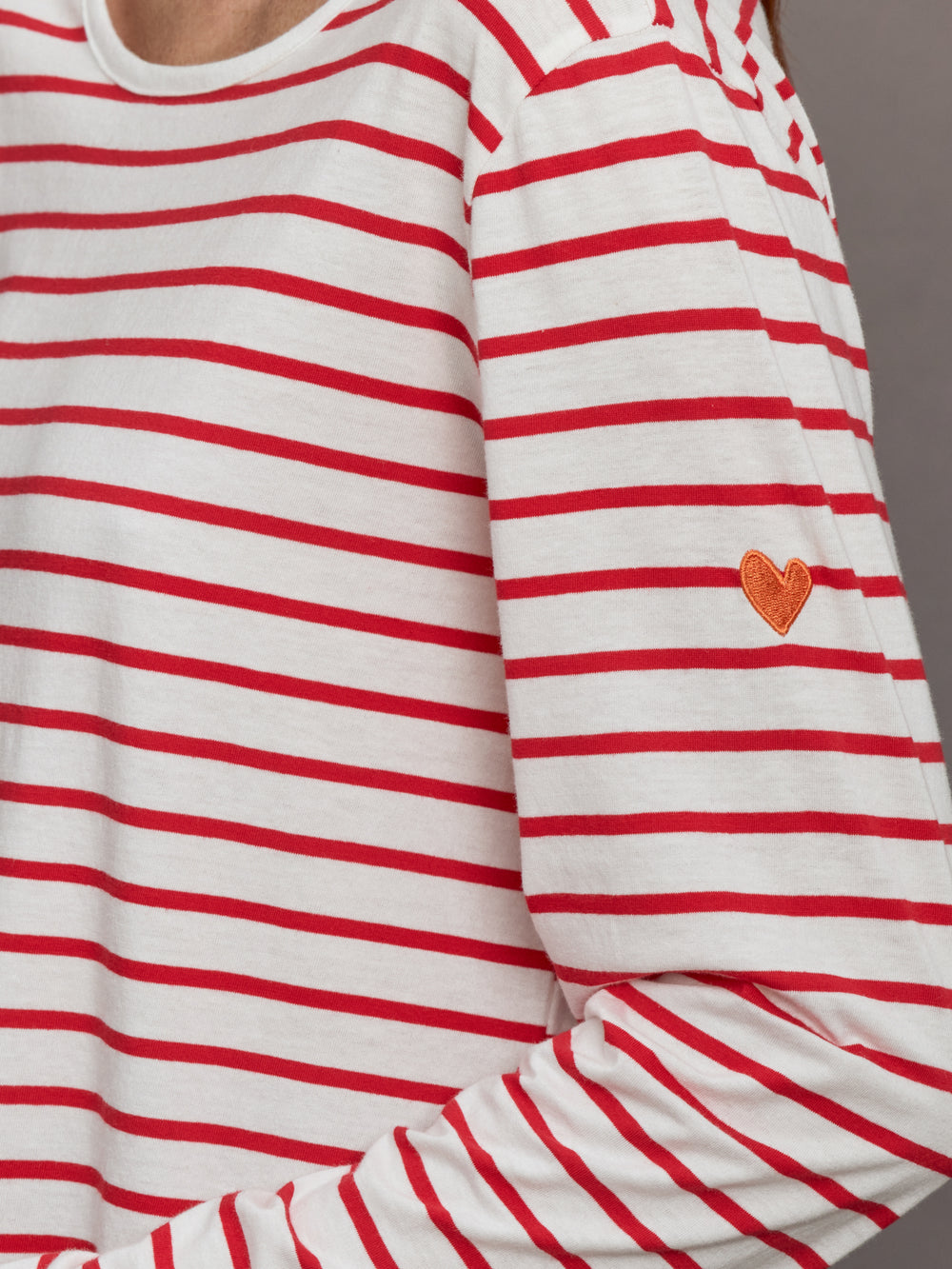 Model wears long-sleeve t-shirt with horizontal white and red stripes and a crew neckline.