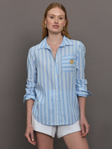 Model wears a striped blue and white buttondown long sleeve with single chest pocket. 