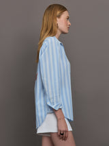 Model wears a striped blue and white buttondown long sleeve with single chest pocket. 
