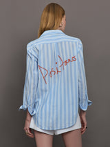 Model wears a striped blue and white buttondown long sleeve with single chest pocket. 